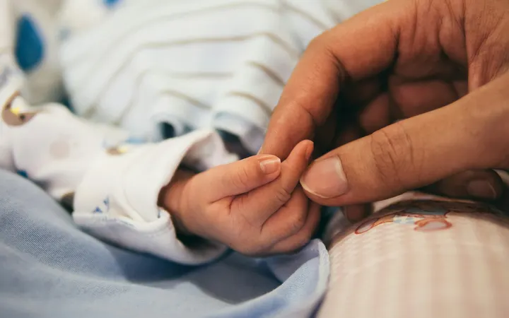 Newborn baby holding a parent's finger